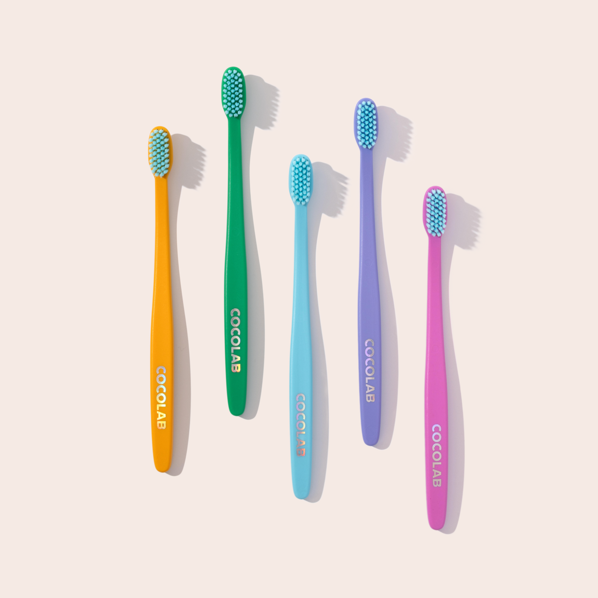 Five colorful Cocobrush toothbrushes arranged together