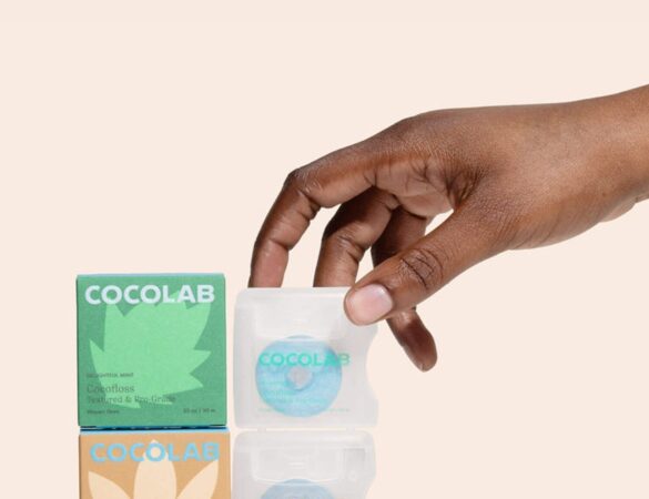 A hand holds Cocofloss spools in a product display