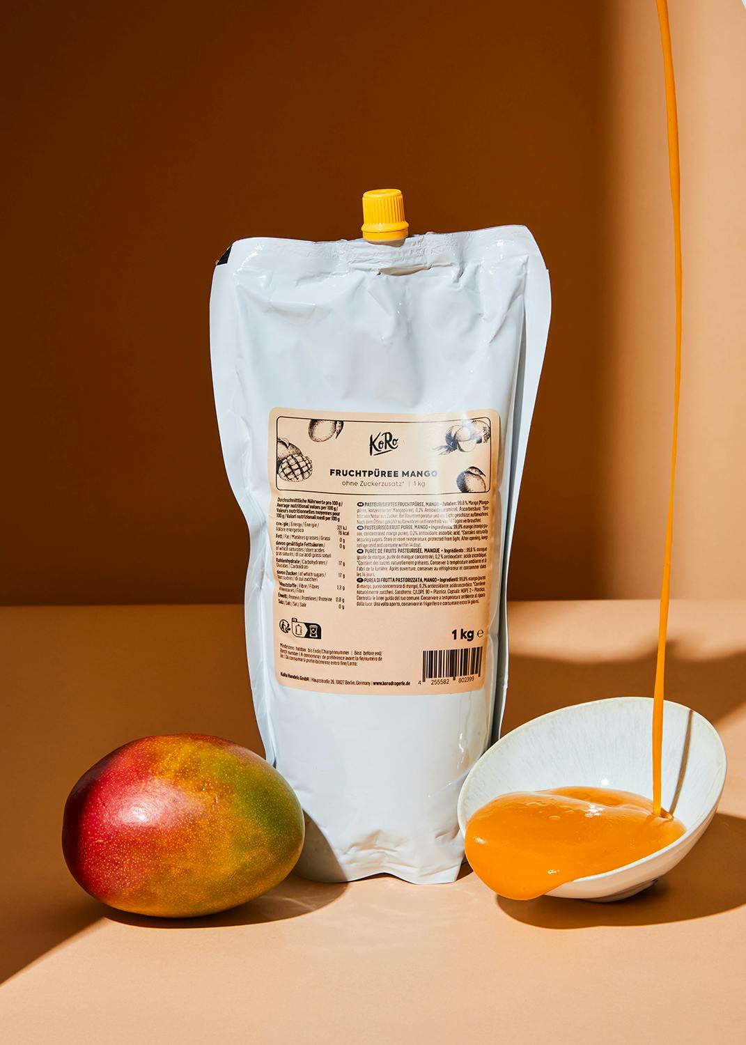 Ein Beutel Mango-Fruchtpüree neben einer Mango