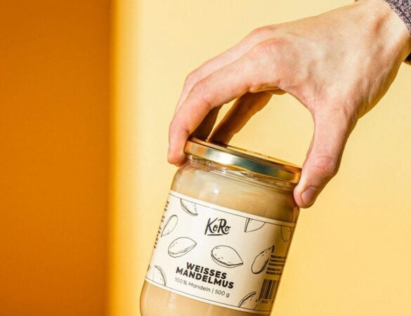 Eine Person hält ein Glas weißes Mandelmus