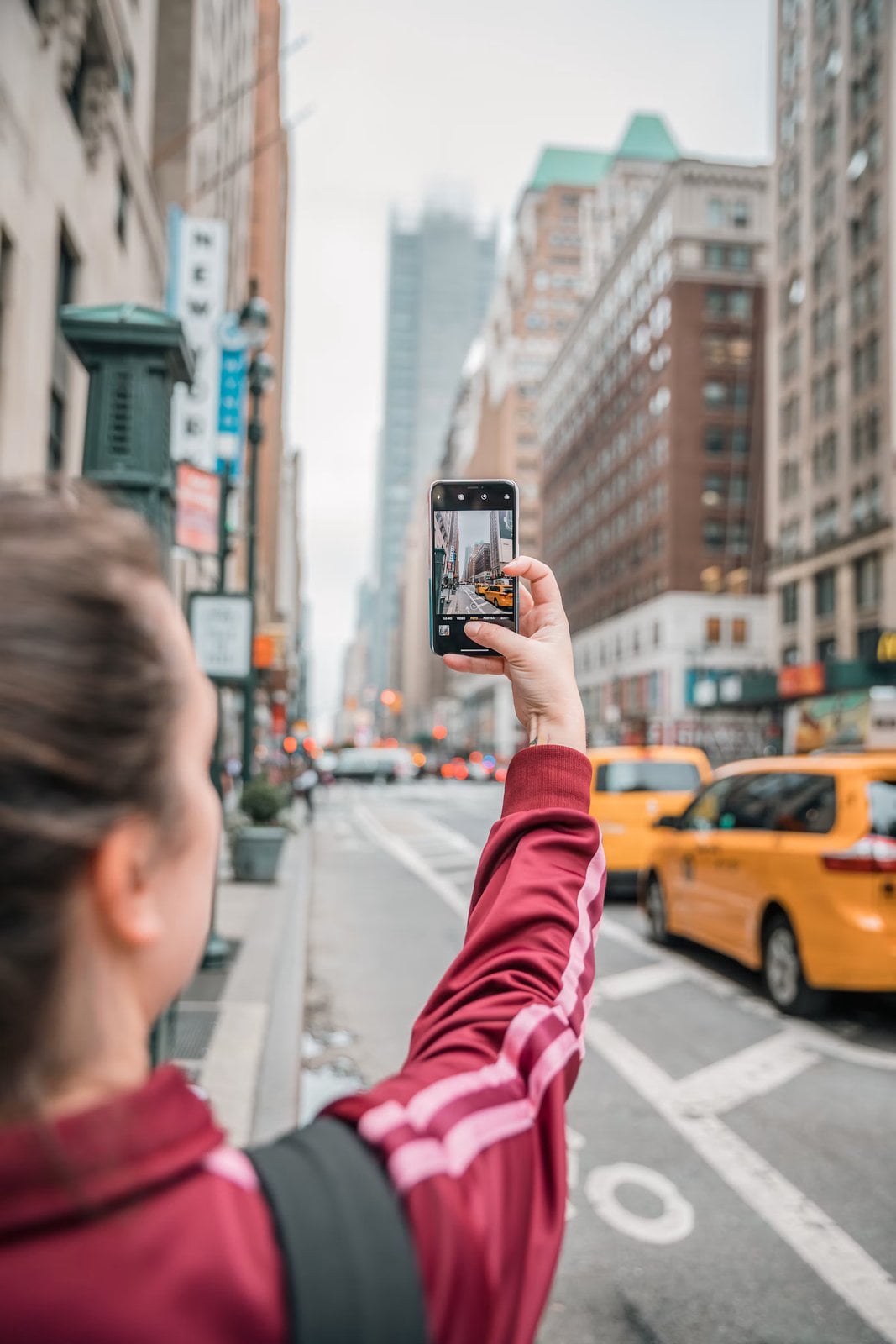 Person using a smartphone to photograph a city street