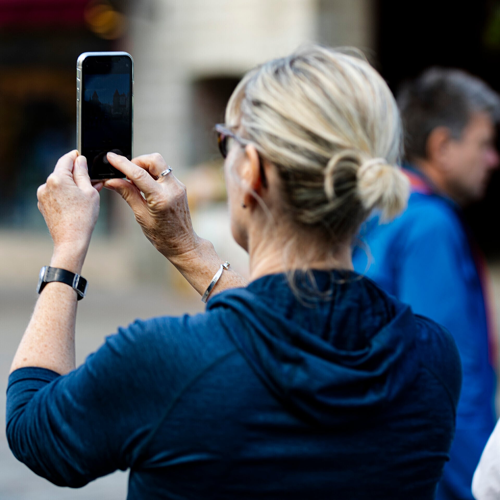 A woman holding a smartphone upright to photograph an outdoor scene