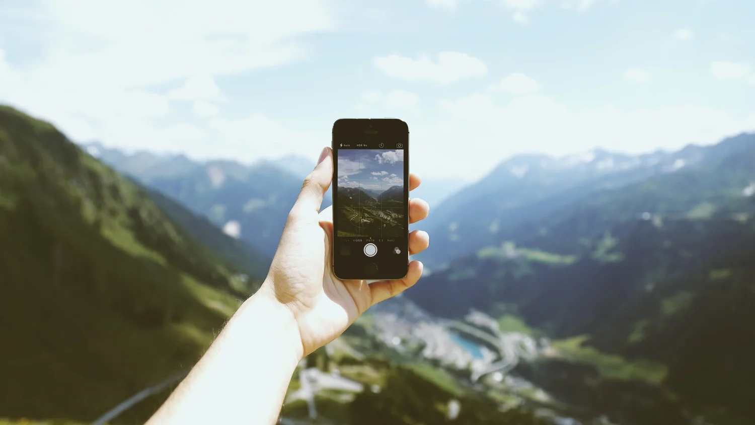 Person using a smartphone to frame a mountain valley