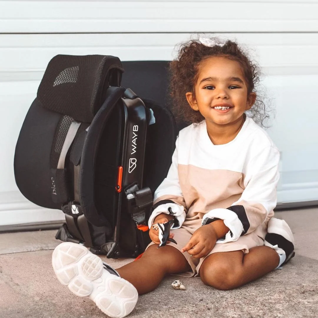 Toddler beside a folded Pico car seat